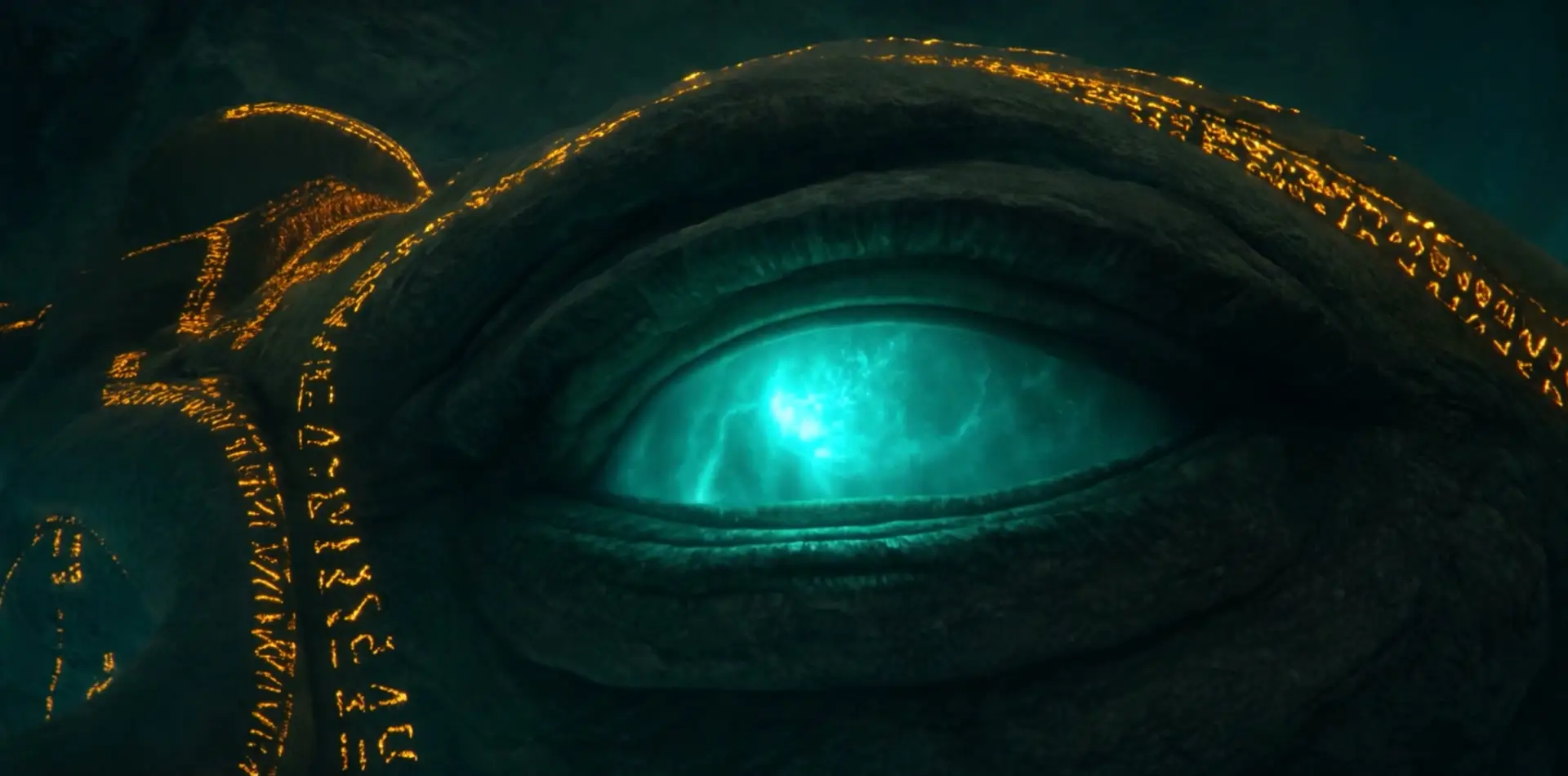 A colossal stone eye lit from within by turquoise light, carved with glowing golden symbols.